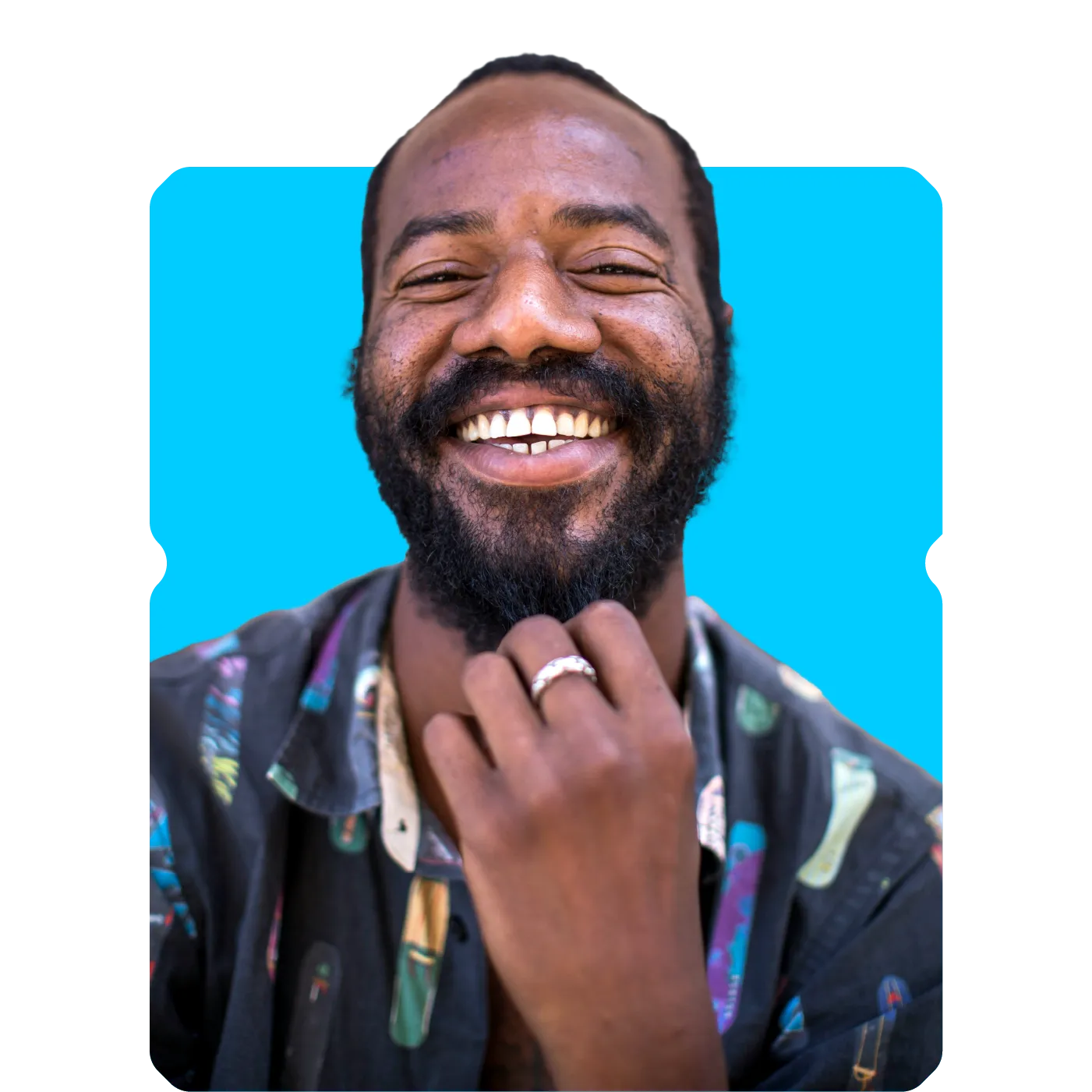 Smiling bearded man wearing a patterned shirt and a ring against a bright blue background
