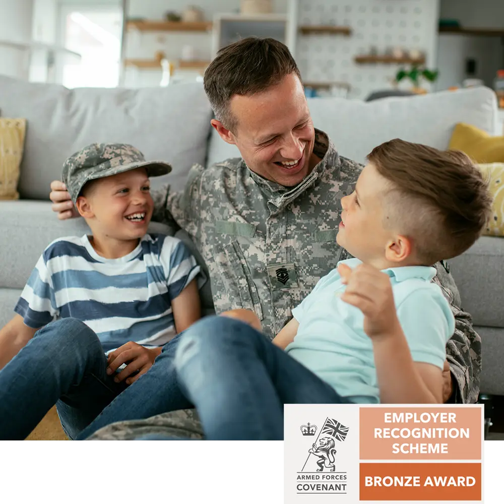 Uniformed service member laughing with two children on a sofa, Armed Forces Covenant Bronze Employer Recognition badge